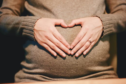 28 weeks pregnant woman making heart hands on her belly