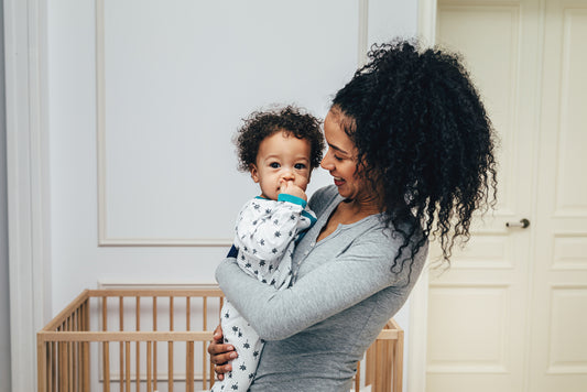 Mom holding baby in nursery feeling good about crib safety 