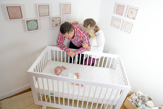 Mom and dad checking in on newborn sleeping in crib