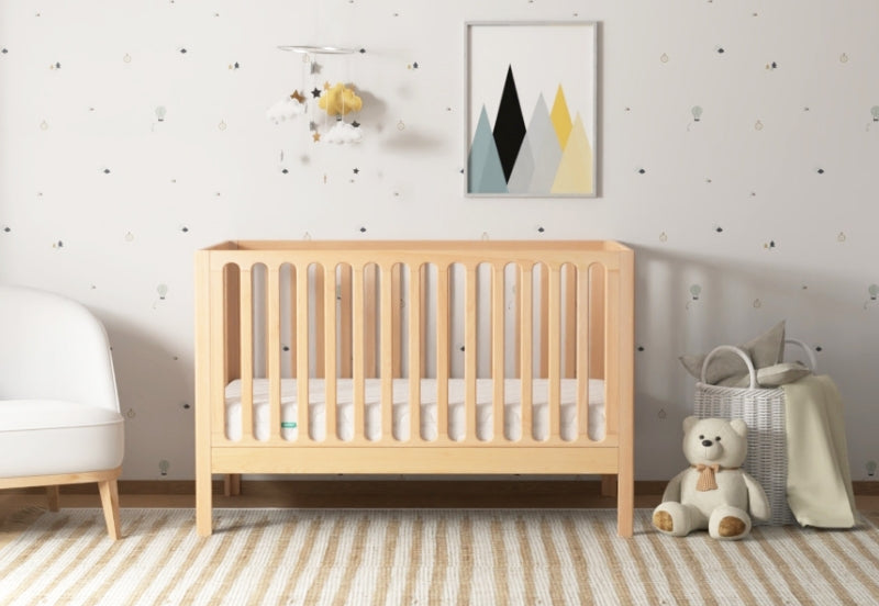 galileo crib in natural color, in nursery with newton mattress, front facing angle