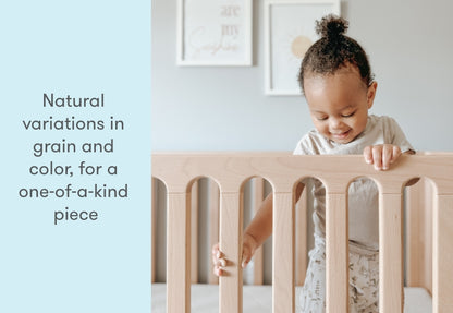 toddler standing up in newton galileo crib in natural color, text reads "natural variations in grain nd color, for a one-of-a-kind piece"